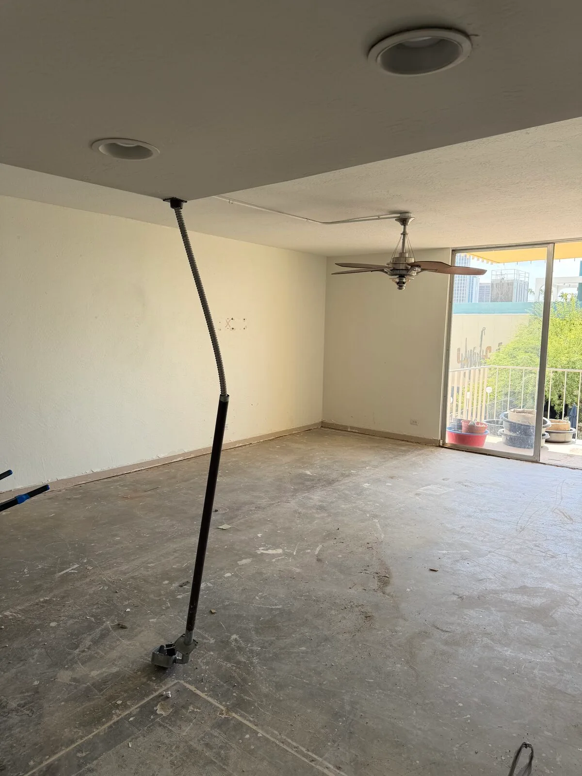 Condo living room stripped of flooring and cabinetry, leaving bare concrete ready for the next trade