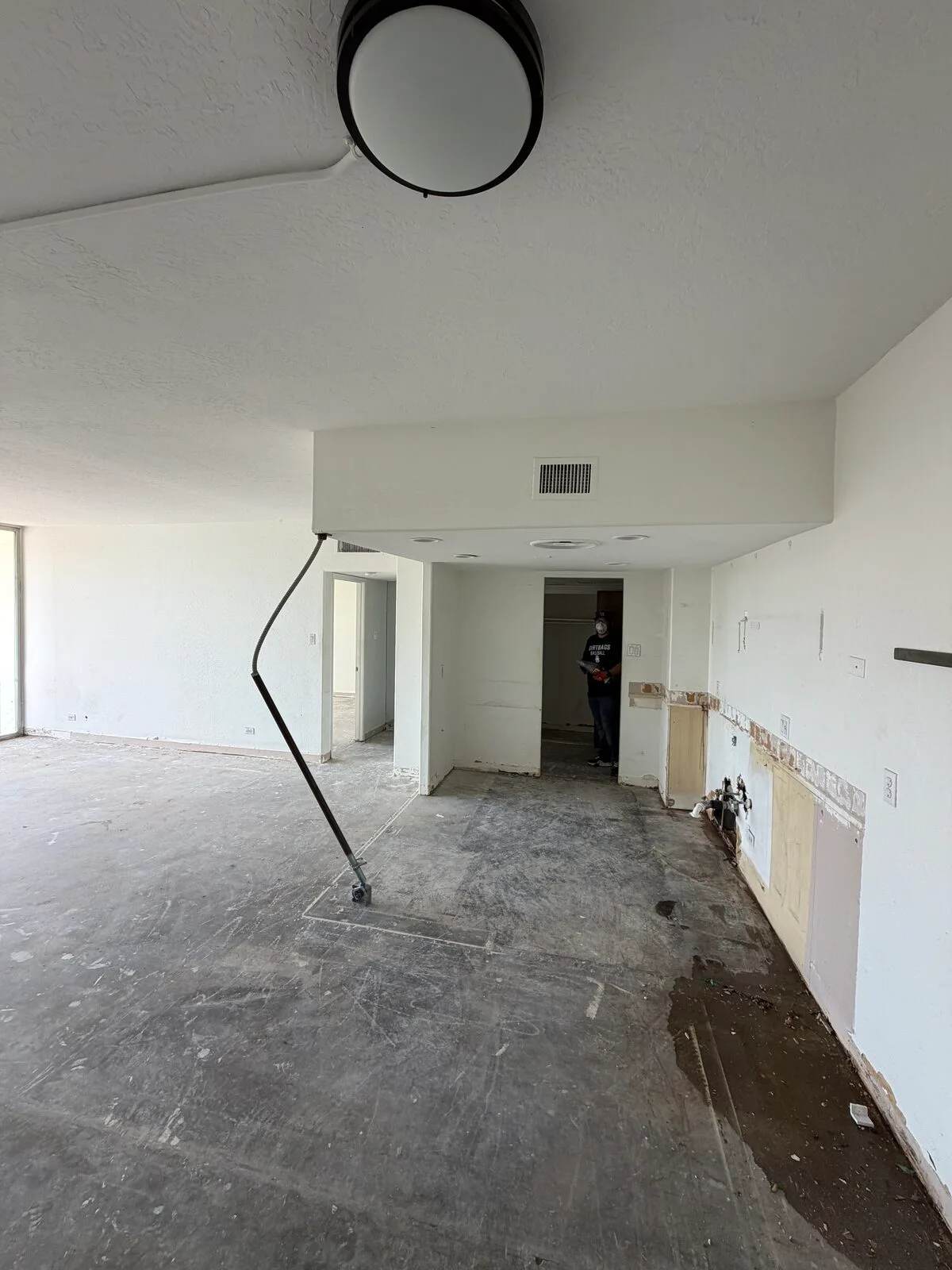 Open condo floor plan after demolition with the kitchen wall opened up and the slab cleaned and cleared