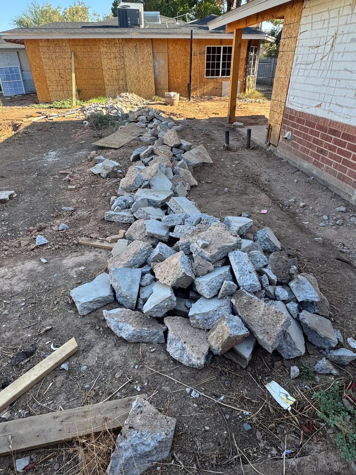 Broken concrete patio slab busted up into a pile of rubble in a backyard ready for haul-off